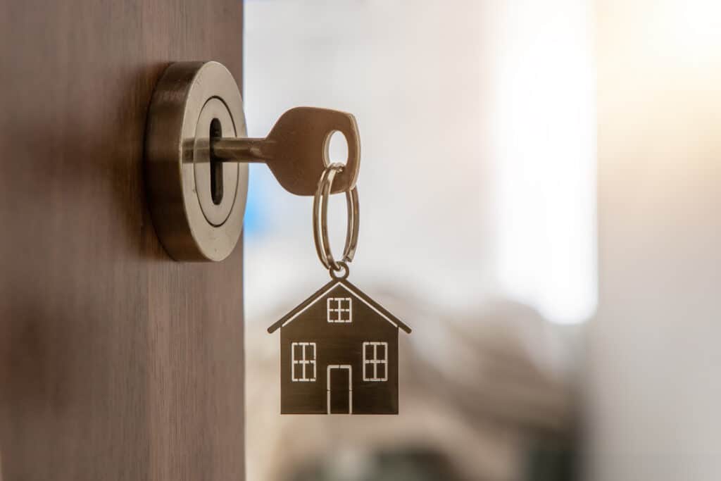 Open door to a new home with key and home shaped keychain. Mortg